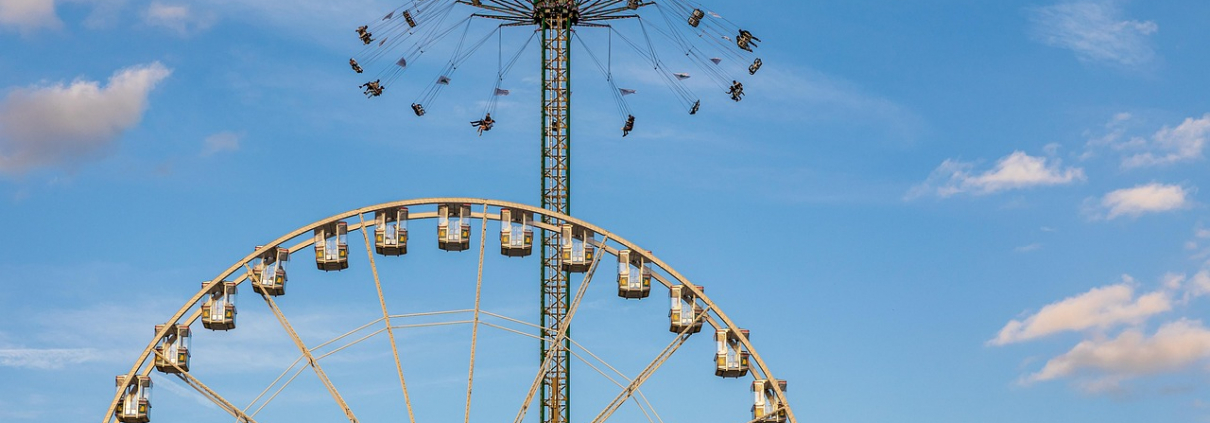 Ein Riesenrad steht vor einem Kettenkarussel.