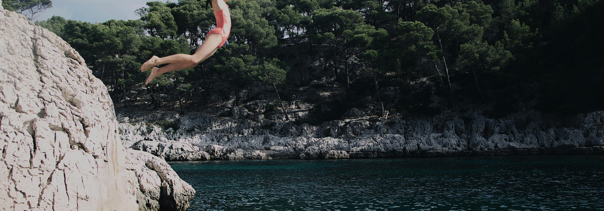 Eine Frau springt mit dem Bauch voraus ins Wasser.